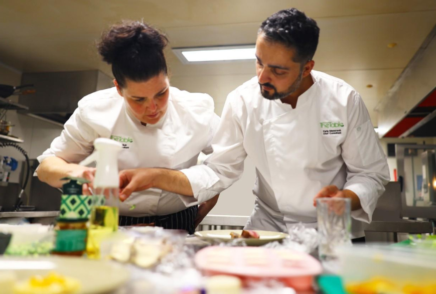 Chefs Natalie Bolt and Faris Almasarweh from The Table Food Consultants collaborating in a commercial kitchen, demonstrating sustainable cooking practices and reducing food waste.